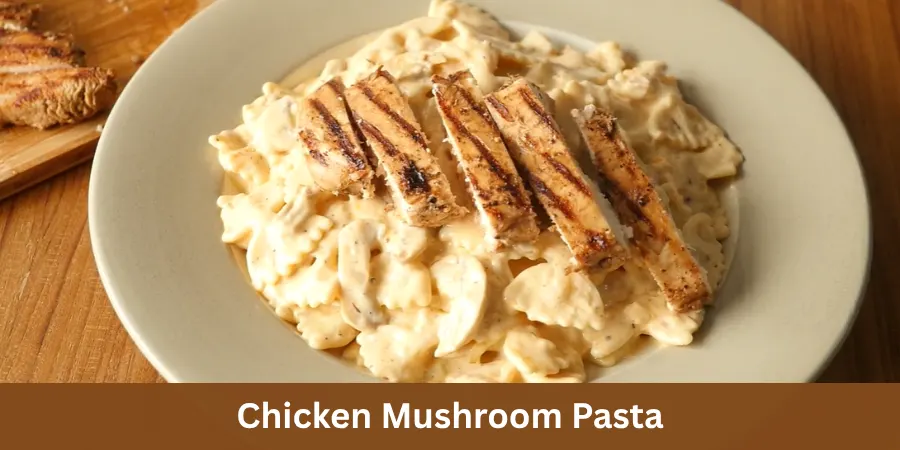 A complete serving of creamy chicken mushroom pasta with tender chicken and mushrooms naturally mixed through the pasta in a simple dining setting, photographed from an elevated three-quarter view.