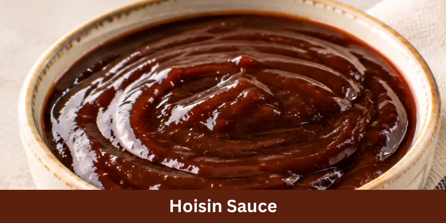 A finished bowl of thick smooth Hoisin Sauce on a clean neutral surface with a subtle spoon nearby, shown in a simple three-quarter food photograph for homemade cooking.
