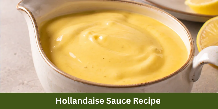 A serving vessel of smooth, creamy Hollandaise Sauce sits in the foreground with a prepared savory dish softly visible behind it on a clean kitchen table, presented as a fresh homemade sauce.