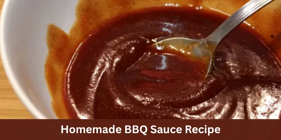 A rustic ceramic bowl filled with thick glossy homemade BBQ sauce on a wooden serving surface, photographed from a three-quarter angle with a simple barbecue serving setting in the background.