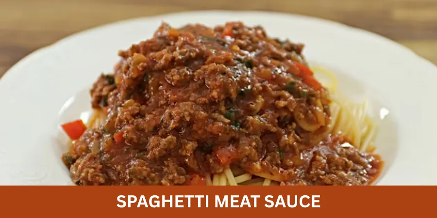 A plate of spaghetti topped with rich tomato-based meat sauce and visible ground meat, served as a warm homemade dinner with a simple fork on a dining table.