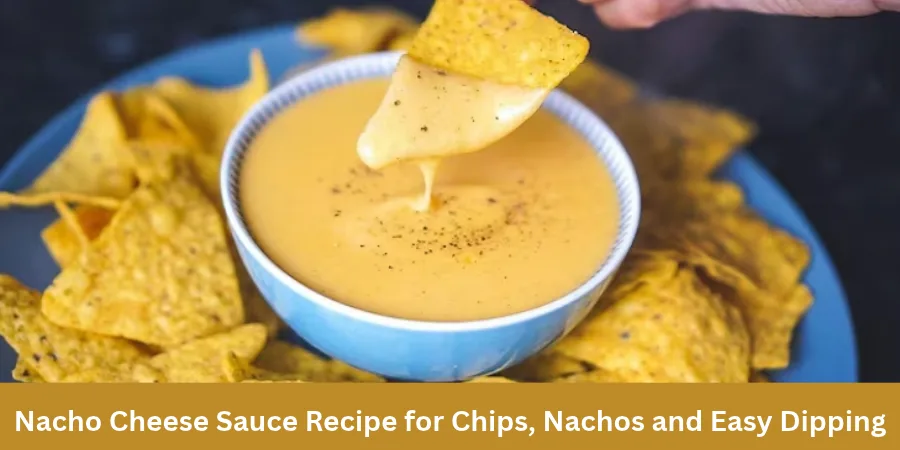 A tortilla chip is dipped into a bowl of smooth Nacho Cheese Sauce on a warm casual serving surface, with additional chips nearby and a softly blurred background.